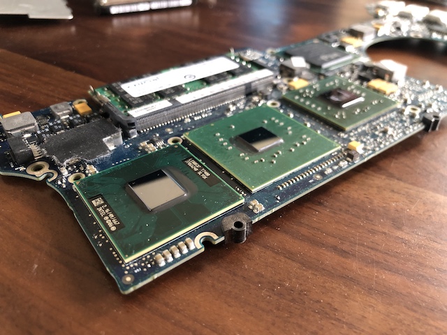 The CPUs and GPU on the motherboard of the 2006 macbook pro, freshly cleaned of thermal paste and setting on a clean walnut coffee table.